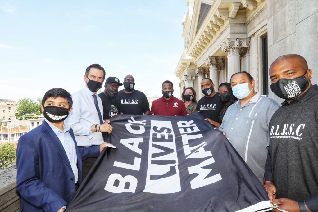 Mayor Steven Fulop and several others hold the Black Lives Matter Flag before itis raised. Flag is black with white lettering